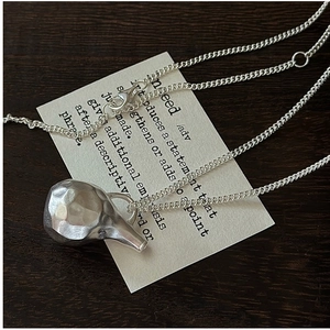 Close-up of S925 silver necklace with hammered matte pendant on a wooden background