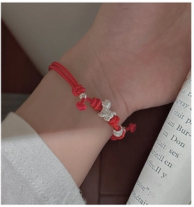 Close-up of S925 silver horse charm on a red braided rope bracelet worn by a model