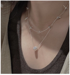 Detail of layered S925 silver sweater chain with thorn link and cylindrical pendant