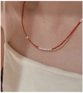 Detail of red spinel and pearl S925 sterling silver necklace on model neck