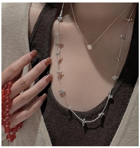 Detail of layered S925 sterling silver sweater chains with bear pendant on knitwear