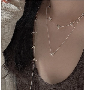 Detail of S925 silver balloon bear necklace and minimalist cube pendant layered on neck
