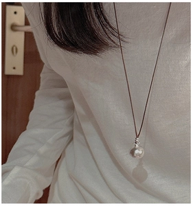 Dettaglio della collana minimalista con ciondolo in argento e cordino in pelle marrone indossata