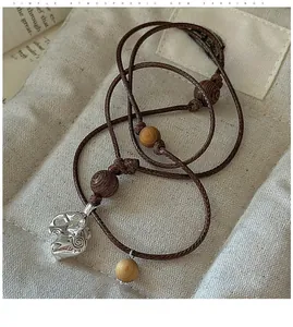 Detail showing an elephant pendant necklace with wooden beads on a linen background