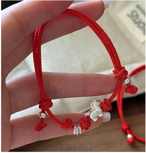 Close-up of red braided rope bracelet with silver Pixiu pendant and beads details