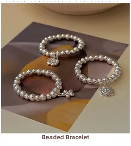 Detail of S925 sterling silver beaded rings featuring apple, flower and smiley pendants
