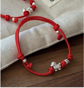 Macro detail of S925 silver horse charm on red braided string bracelet for wealth