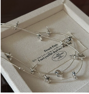 Detail of silver double-layered sweater chain with bird and star charms on display