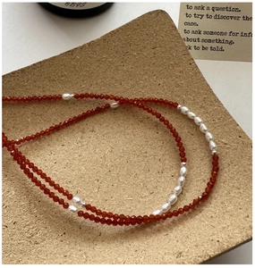 Detail of S925 silver necklace with red spinel beads and baroque pearls on stone tray