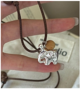 Detail of S925 silver elephant pendant with ornate patterns and wooden bead on brown cord