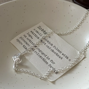 Minimalist S925 silver knot necklace with a teardrop zircon pendant in a ceramic bowl