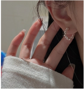 Gros plan de boucles d'oreilles créoles en argent S925 avec texture géométrique sur modèle
