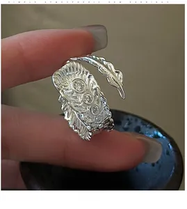 Macro shot of silver feather ring showing vintage design and four inlaid zircon crystals