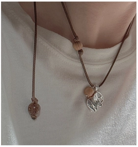Close-up of S925 sterling silver elephant pendant with brown wooden beads and cord