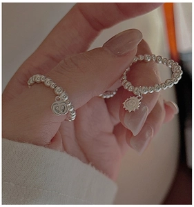 Detail shot of S925 sterling silver beaded rings with apple and smiley face charms