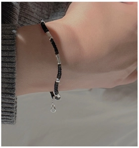 Close-up of a braided rope bracelet with silver bamboo tubes on a woman's wrist