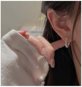 Détail macro de boucles d'oreilles vagues argentées avec texture vintage scintillante