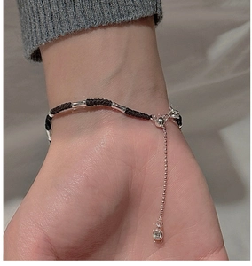 Macro detail of S925 silver woven rope bracelet with metallic tubes and crystal charm