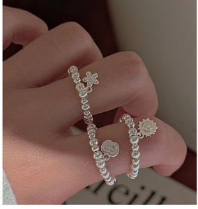 Close-up of S925 sterling silver beaded rings with flower, sun, and heart charms