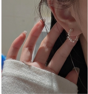 Gros plan d'une boucle d'oreille S925 argentée texturée au design géométrique facetté