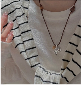 Detail of vintage silver dragon pendant with brown braided cord and wooden beads on model