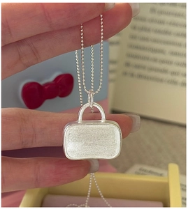 Close-up of S925 sterling silver handbag pendant with brushed texture on bead chain