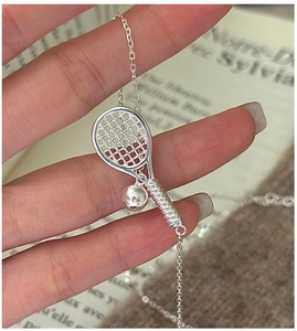 Detailed view of an S925 silver tennis racket necklace on a French vintage book background