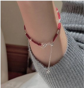 Close-up of a handmade red woven rope bracelet with S925 sterling silver charms and beads