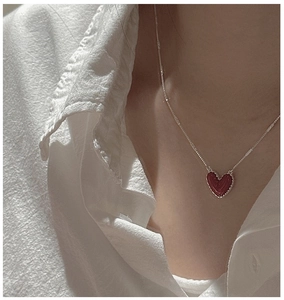 Dettaglio di un ciondolo a cuore in smalto rosso su una sottile catena d'argento