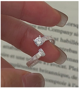 Macro detail of silver S925 bypass ring with textured band and sparkling round zircon