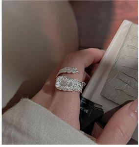 Detailed view of silver feather ring with zircon stones on a person's hand