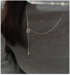 Detail view of S925 sterling silver tennis racket necklace on grey knit sweater
