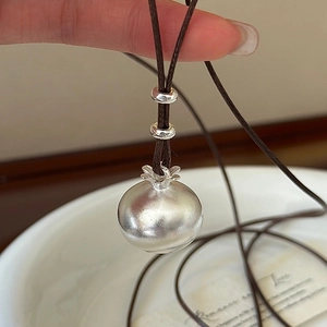 Ciondolo in argento S925 a forma di cachi con cordino in pelle marrone scuro in mano