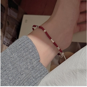 Detail of red woven silver bead bracelet showing adjustable closure on wrist