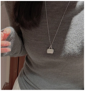Detail of S925 sterling silver handbag pendant necklace on a dark knit sweater