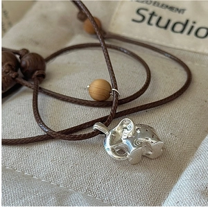 Macro shot of S925 sterling silver elephant pendant with braided cord and wood beads