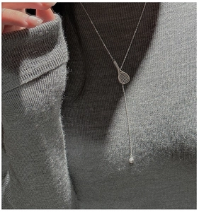 Detail of S925 sterling silver tennis racket Y-necklace pendant on grey knitwear