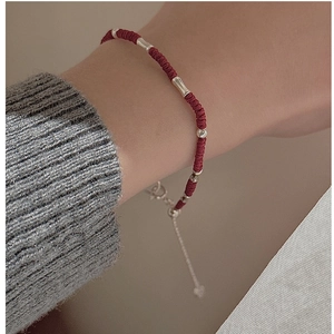 Detail view of red braided rope bracelet with silver beads and lobster clasp closure