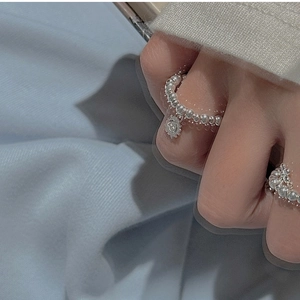 Detailed shot of a silver beaded elastic ring featuring a sun charm on a finger