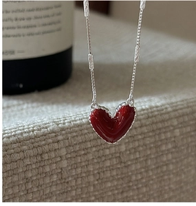 Dettaglio ravvicinato del ciondolo a cuore rosso con bordo seghettato su catena d'argento