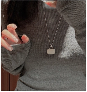 Close-up of S925 sterling silver ball chain necklace with bag pendant on knit sweater