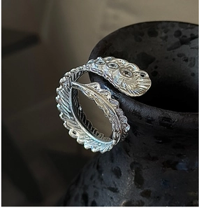Detailed close-up of vintage S925 silver feather ring with intricate texture on dark pot