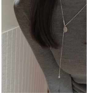 Detail of S925 sterling silver Y-shaped tennis racket necklace on a grey sweater