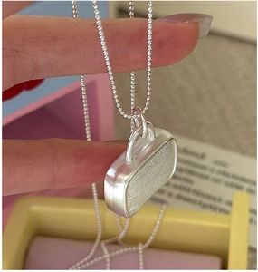 Macro shot of a S925 silver handbag pendant with brushed texture and beaded chain