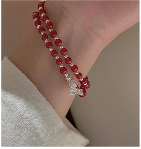 Détail d'un bracelet double couche en agate rouge avec charm cheval à bascule en argent