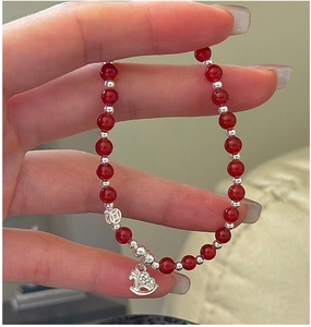 Gros plan d'un charm cheval en argent S925 et perles d'agate rouge sur bracelet élastique