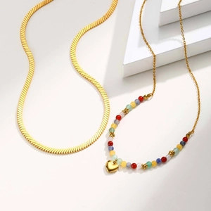 Detail of gold layered necklaces with flat blade chain and multi-color beaded heart charm