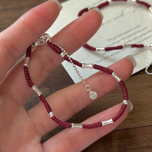Minimalist red woven rope bracelet with S925 silver bamboo tubes on a wooden background