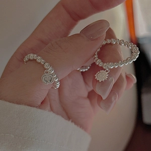 Minimalist S925 sterling silver beaded rings featuring apple and smiley sun charms on the hand