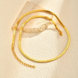 Layered gold blade chain necklace with heart pendant on stone decor, 45-degree angle view